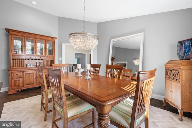 dining space featuring a chandelier, parquet flooring, and baseboards