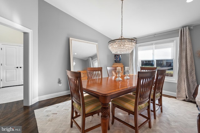 dining room with lofted ceiling, wood finished floors, baseboards, and a chandelier