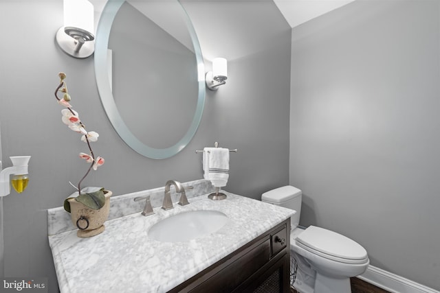 bathroom featuring toilet, vanity, and baseboards