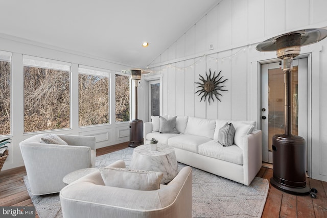 living room featuring vaulted ceiling, hardwood / wood-style flooring, and a decorative wall