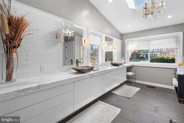 bathroom with a notable chandelier, lofted ceiling, recessed lighting, baseboards, and vanity