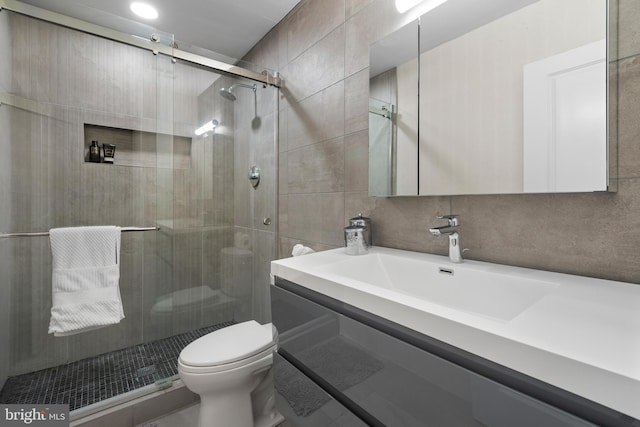 full bath featuring vanity, a stall shower, tile walls, toilet, and backsplash