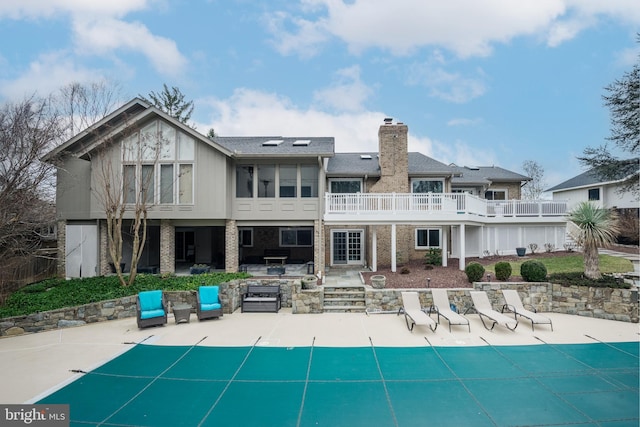 back of property with a covered pool, a patio, and a chimney