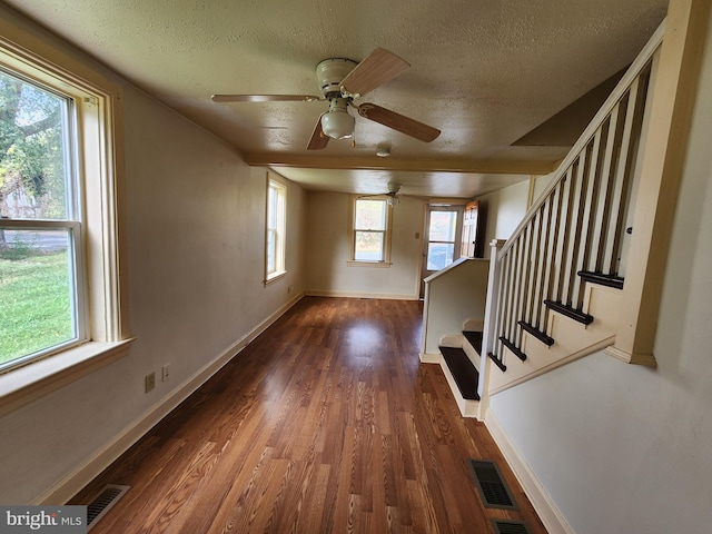 unfurnished living room with visible vents, baseboards, wood finished floors, and stairway