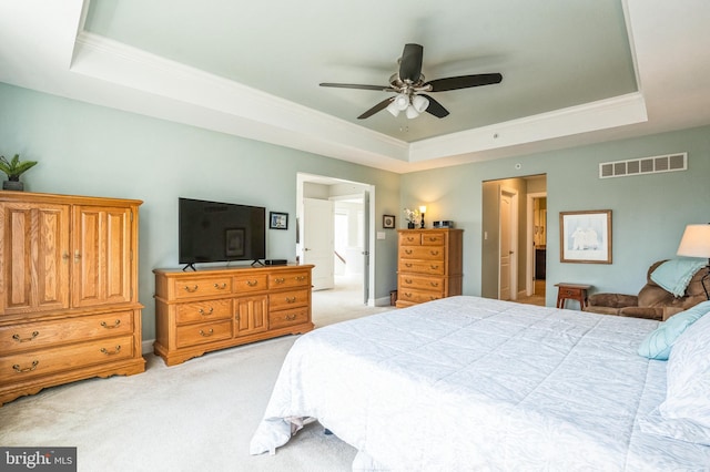 bedroom featuring light carpet, visible vents, a tray ceiling, and ornamental molding