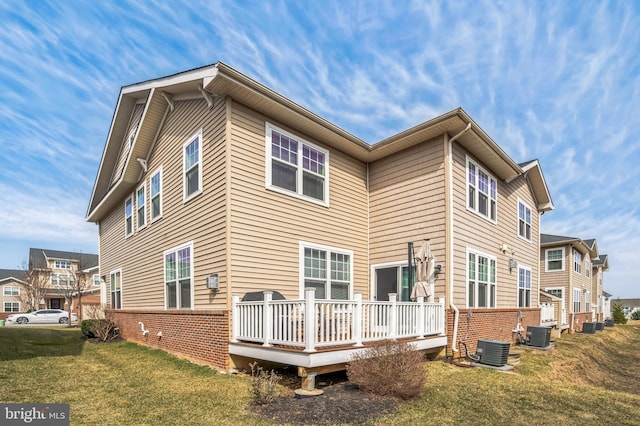 back of property with a yard, central air condition unit, brick siding, and a deck