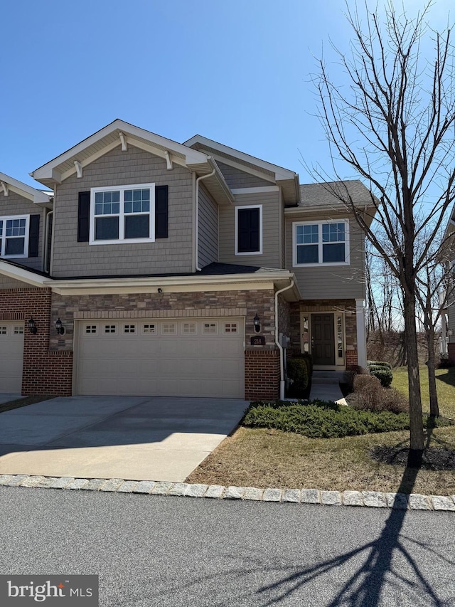 view of front facade with concrete driveway, an attached garage, brick siding, and stone siding