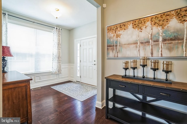 entryway with visible vents, dark wood-style floors, wainscoting, and a decorative wall