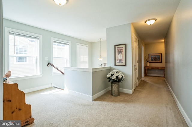 corridor featuring carpet flooring, an upstairs landing, and baseboards