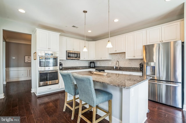 kitchen featuring stainless steel appliances, visible vents, dark wood-style floors, and a center island