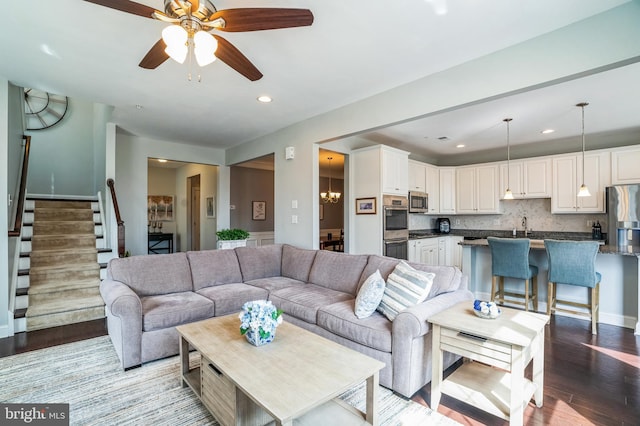 living room with baseboards, stairs, recessed lighting, ceiling fan with notable chandelier, and wood finished floors