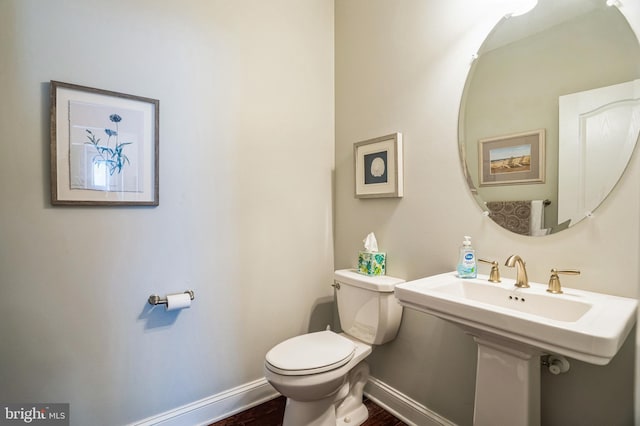 bathroom featuring toilet, wood finished floors, and baseboards