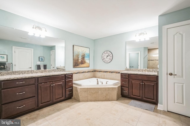 full bath with tiled shower, two vanities, a garden tub, and a sink