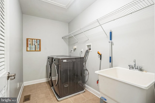 clothes washing area featuring visible vents, laundry area, light tile patterned flooring, washer and dryer, and a sink