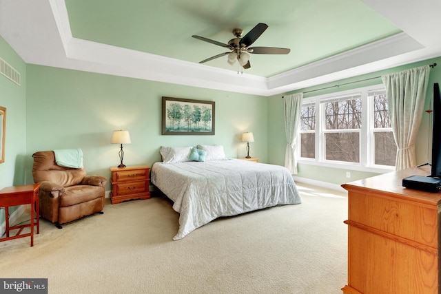 carpeted bedroom featuring baseboards, a raised ceiling, ceiling fan, and crown molding