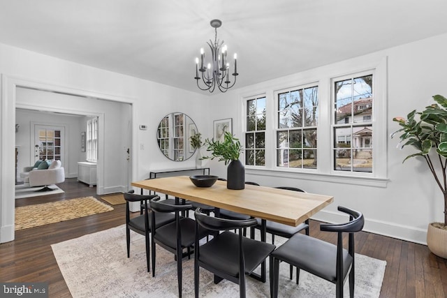 dining area with a chandelier, baseboards, and wood-type flooring