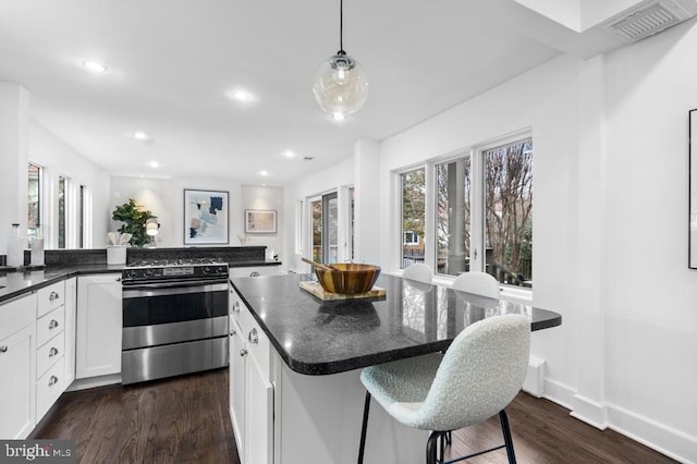 kitchen with a wealth of natural light, white cabinets, dark wood-style floors, and stainless steel gas range