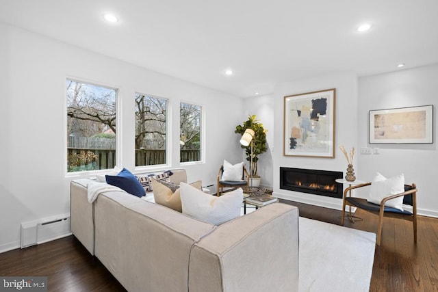 living area featuring baseboards, a baseboard radiator, recessed lighting, a glass covered fireplace, and dark wood-style flooring