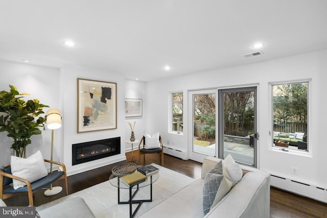 living room featuring visible vents, a baseboard heating unit, and wood finished floors