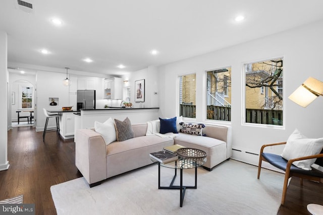 living area with recessed lighting, visible vents, arched walkways, and dark wood-style flooring