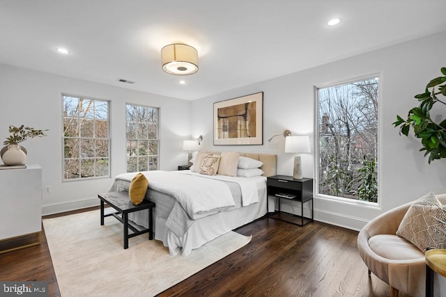 bedroom with multiple windows, dark wood-style floors, and visible vents