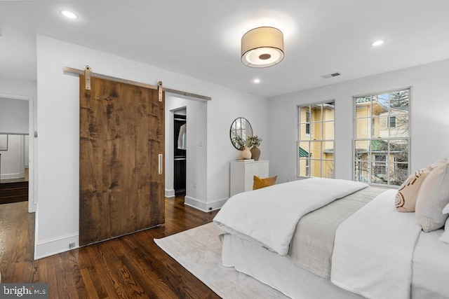 bedroom with recessed lighting, baseboards, a barn door, and wood finished floors