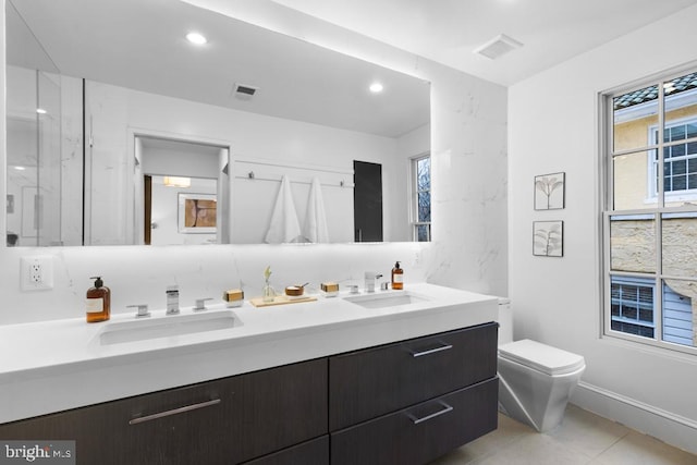 full bath with double vanity, toilet, visible vents, and a sink