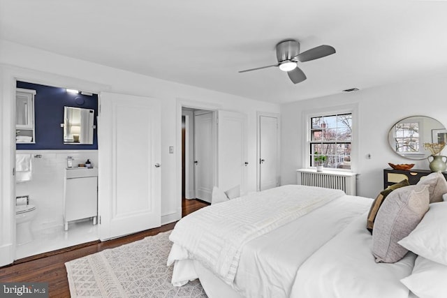 bedroom featuring a ceiling fan, wood finished floors, visible vents, and ensuite bathroom