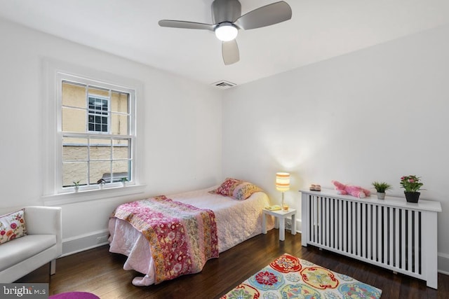 bedroom with radiator, a ceiling fan, wood finished floors, visible vents, and baseboards