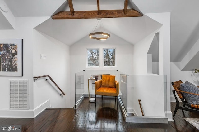 living area with hardwood / wood-style floors, visible vents, baseboards, lofted ceiling with beams, and an upstairs landing