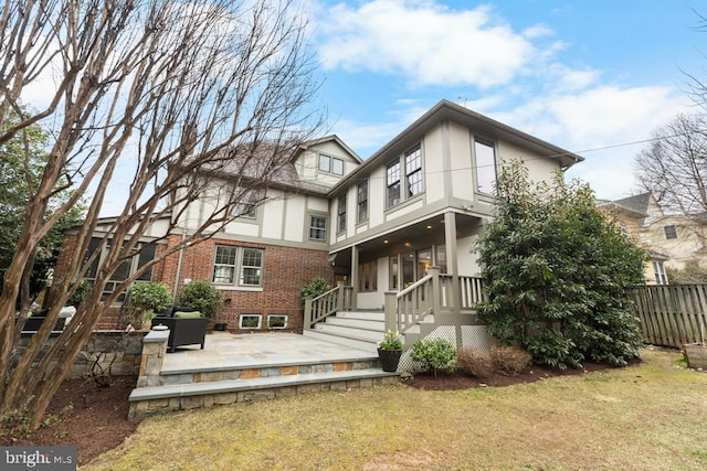 rear view of property featuring brick siding, fence, a yard, a balcony, and a patio area