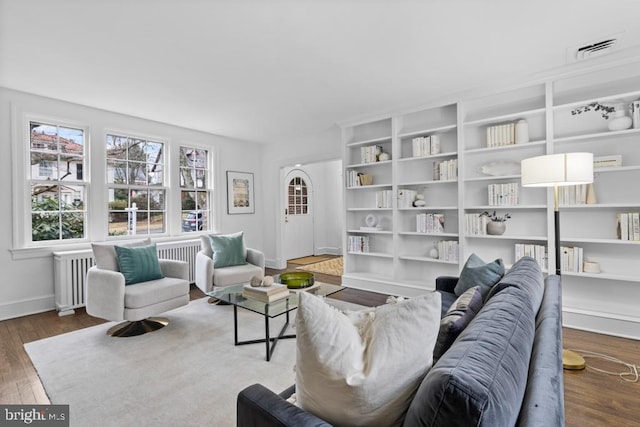 living area with visible vents, radiator, baseboards, and wood finished floors