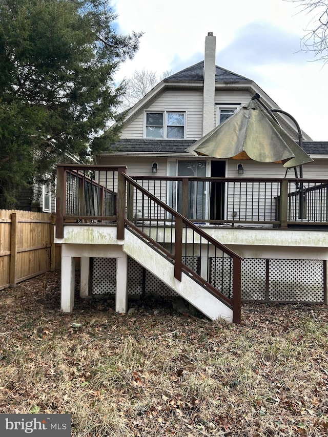 back of house featuring a shingled roof, stairs, a deck, and fence