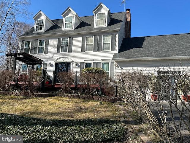 view of front of house with a front lawn, roof with shingles, and a chimney