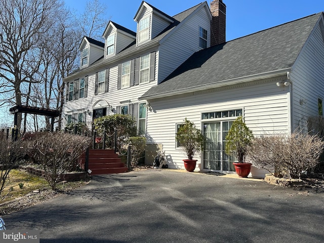 exterior space with an attached garage, a chimney, and a shingled roof