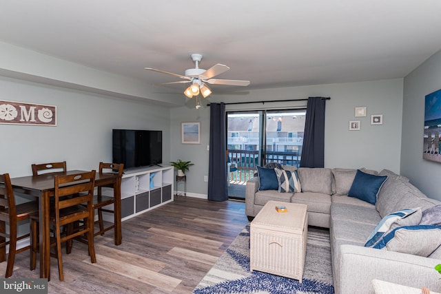 living area with a ceiling fan, wood finished floors, and baseboards