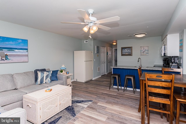 living room with a ceiling fan, wood finished floors, and baseboards