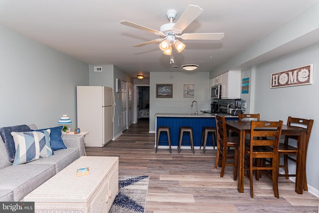 dining room featuring visible vents, light wood-style flooring, baseboards, and a ceiling fan