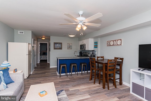 dining area featuring visible vents, baseboards, wood finished floors, and a ceiling fan