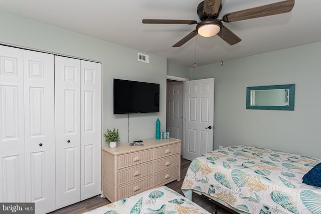 bedroom with a closet, dark wood-style floors, ceiling fan, and visible vents