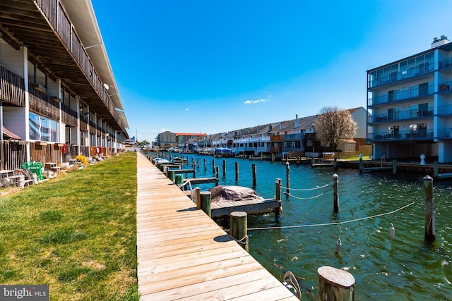 view of dock with a yard and a water view