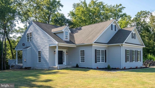 new england style home featuring a front lawn and a shingled roof