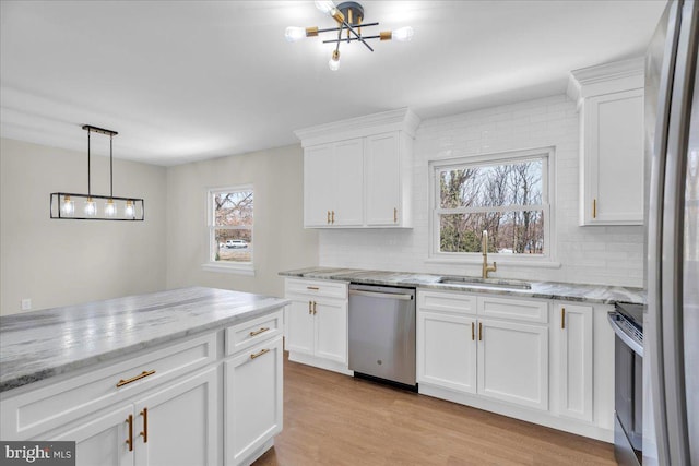 kitchen featuring a sink, stainless steel appliances, light wood-type flooring, and backsplash