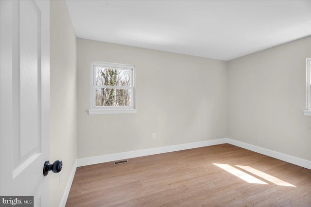 empty room featuring visible vents, baseboards, and wood finished floors