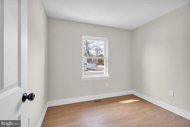 spare room with visible vents, baseboards, and wood finished floors