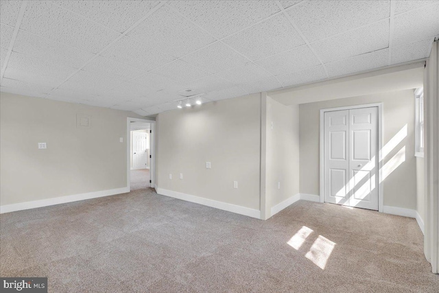 interior space with track lighting, baseboards, a paneled ceiling, and carpet