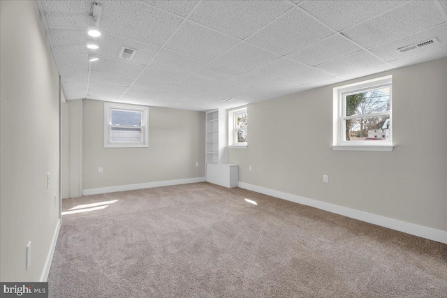 basement with visible vents, carpet, and a healthy amount of sunlight