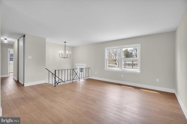 unfurnished room with baseboards, an inviting chandelier, and wood finished floors