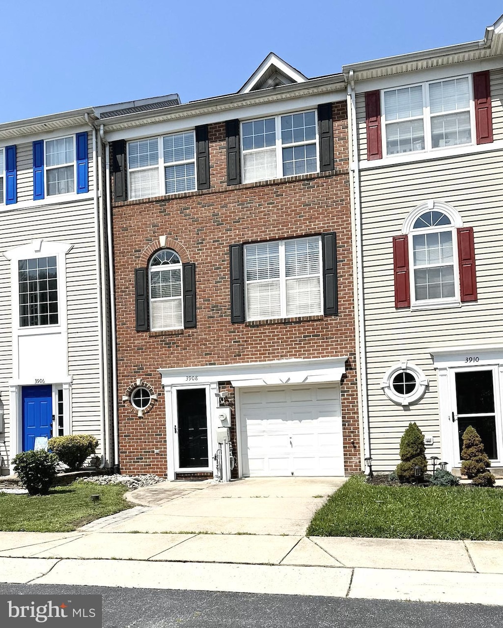 multi unit property featuring an attached garage, brick siding, and driveway