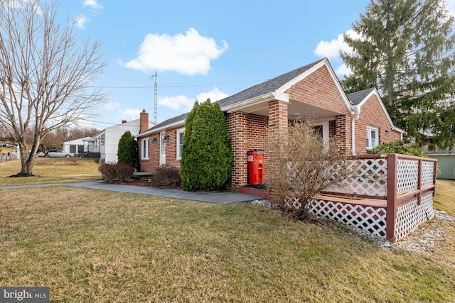 view of front facade with a front lawn, brick siding, and a wooden deck